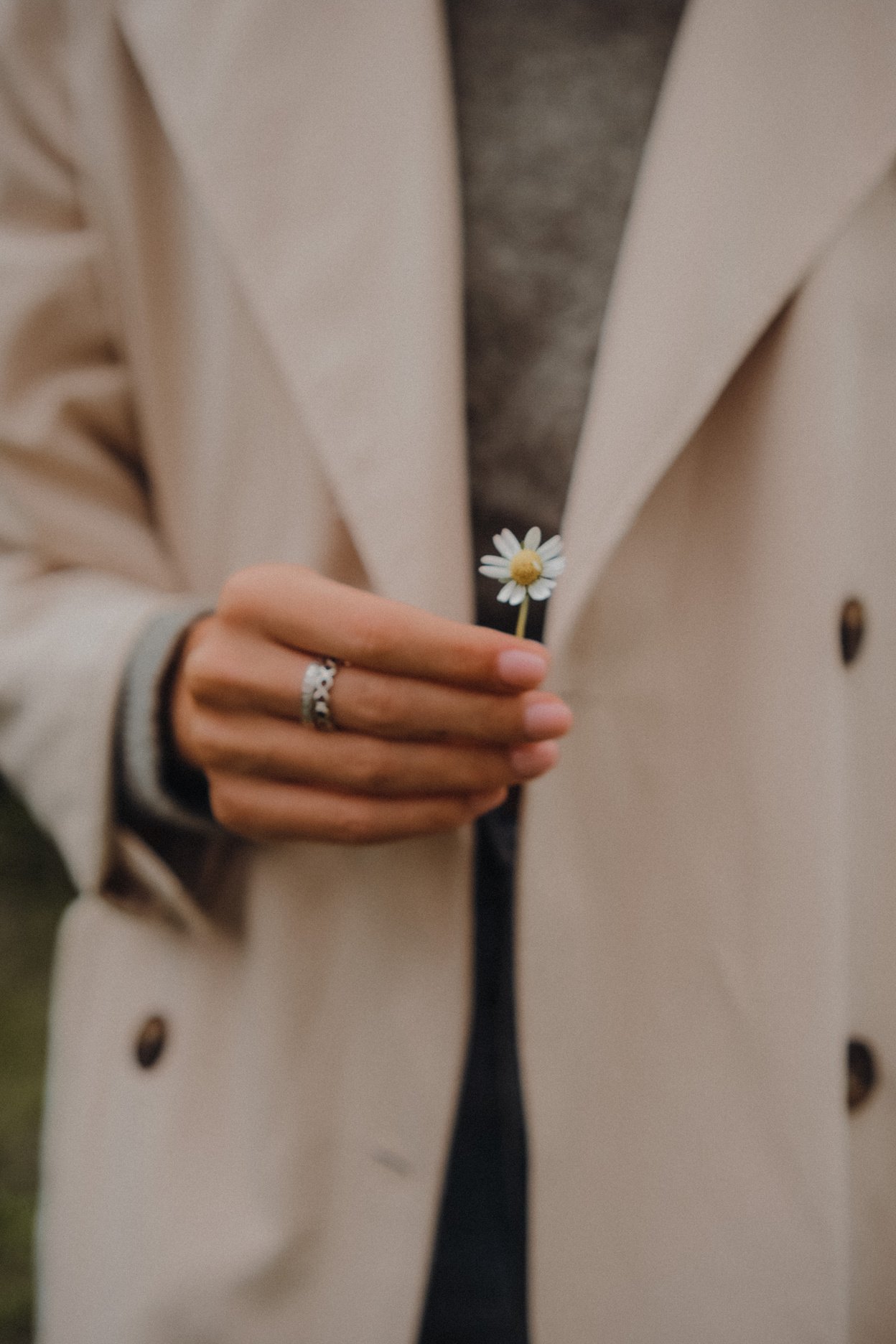 A Person in Beige Coat Holding White Flower